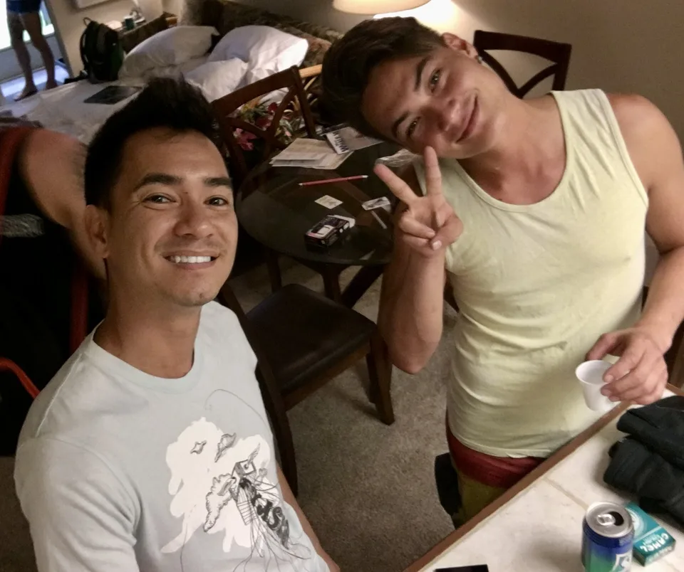 Andre and a friend throwing peace signs indoors